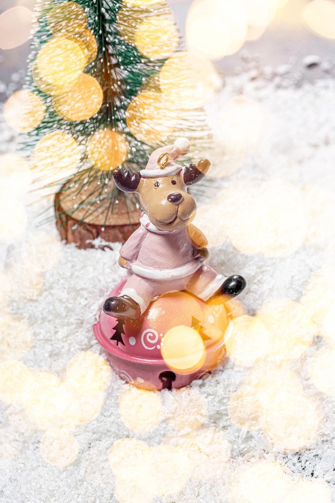 Toy deer on white snow with Christmas tree and Golden bokeh background (Flip 2019)