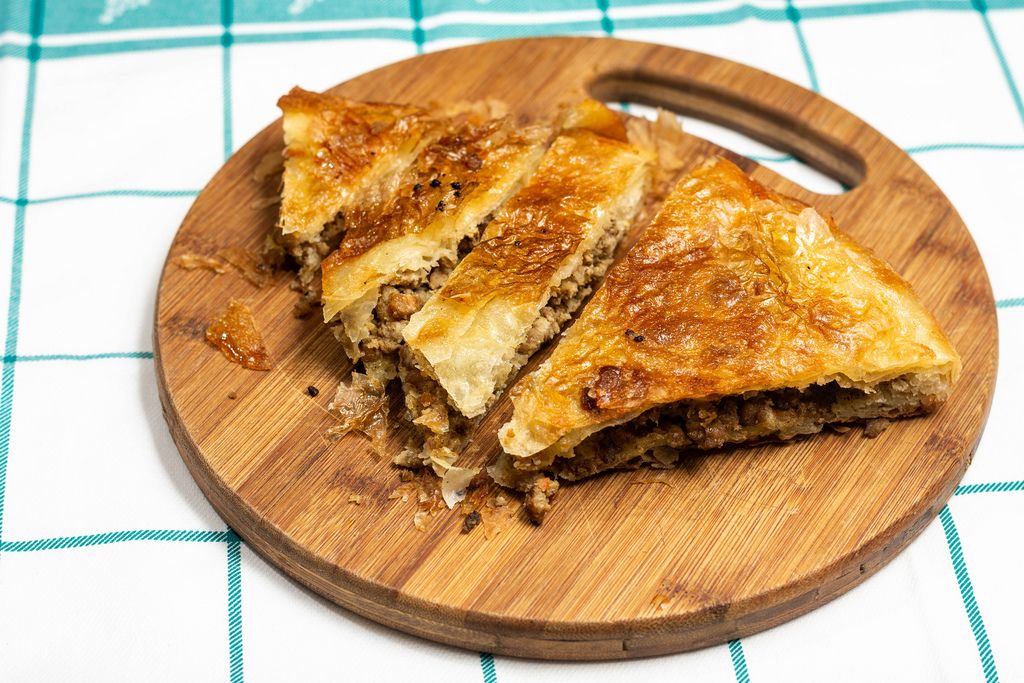 Traditional balkan burek pie with meat sliced and served on wooden board