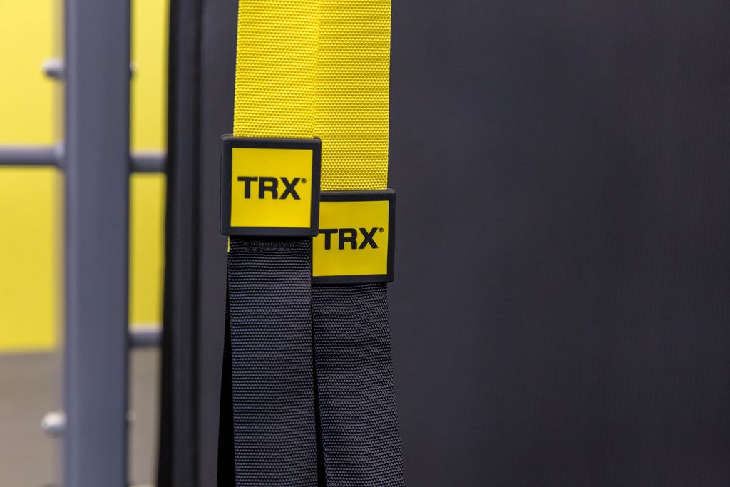 TRX Suspension Schlingentrainer für Fitnessübungen, gelb-schwarzer Gurt mit Logoaufdruck auf der Fibo in Köln