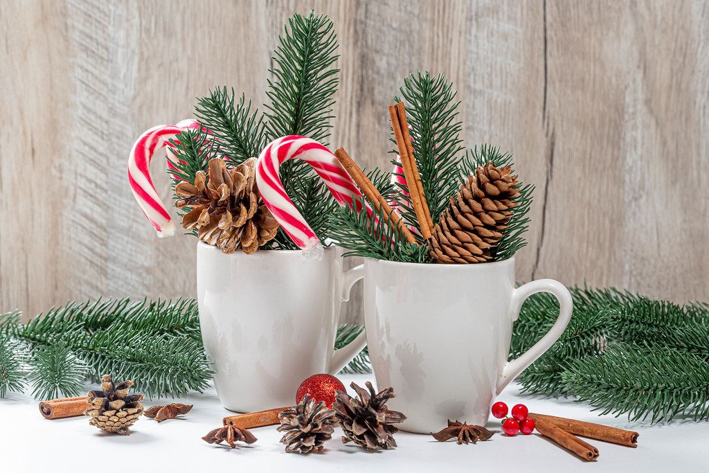 Two cups with lollipops, cones and branches of the Christmas tree. Festive winter background