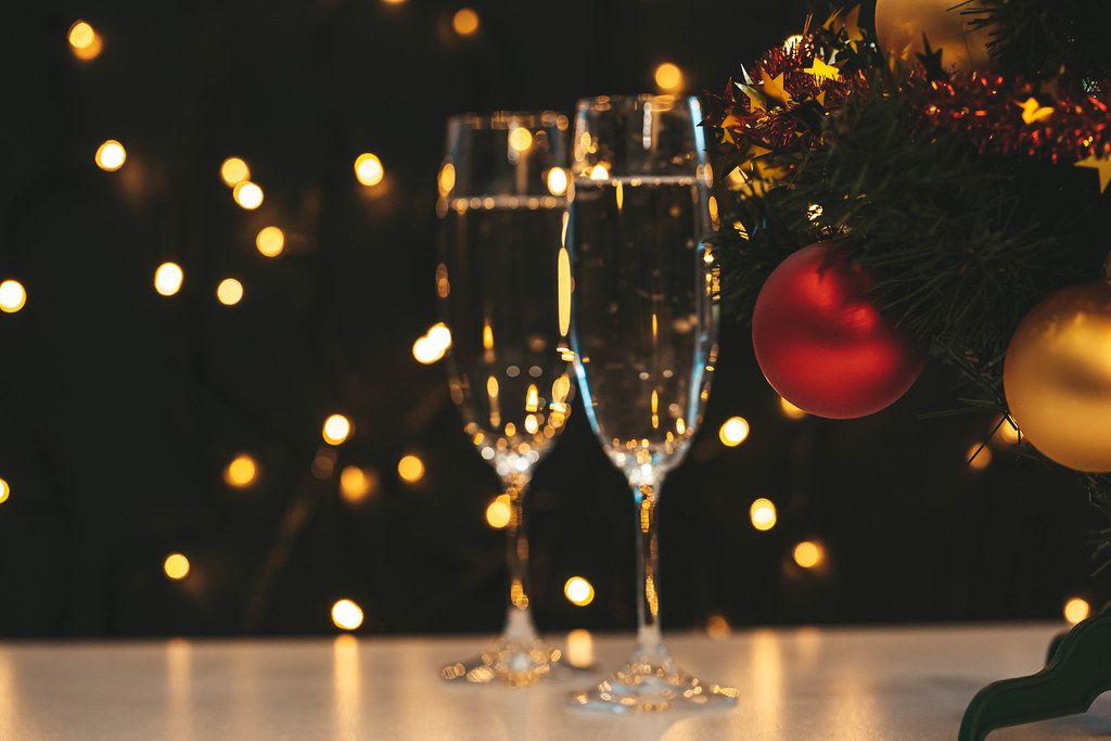 Two glasses of champagne and Christmas tree on a blurry background of a luminous garland