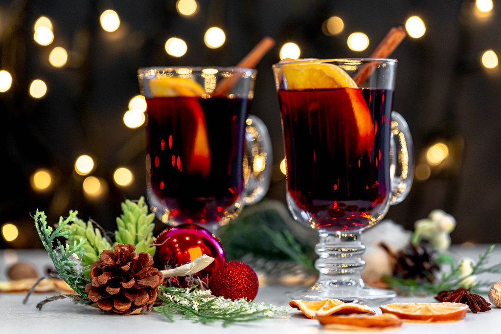Two glasses of mulled wine with christmas decor and glowing garland background