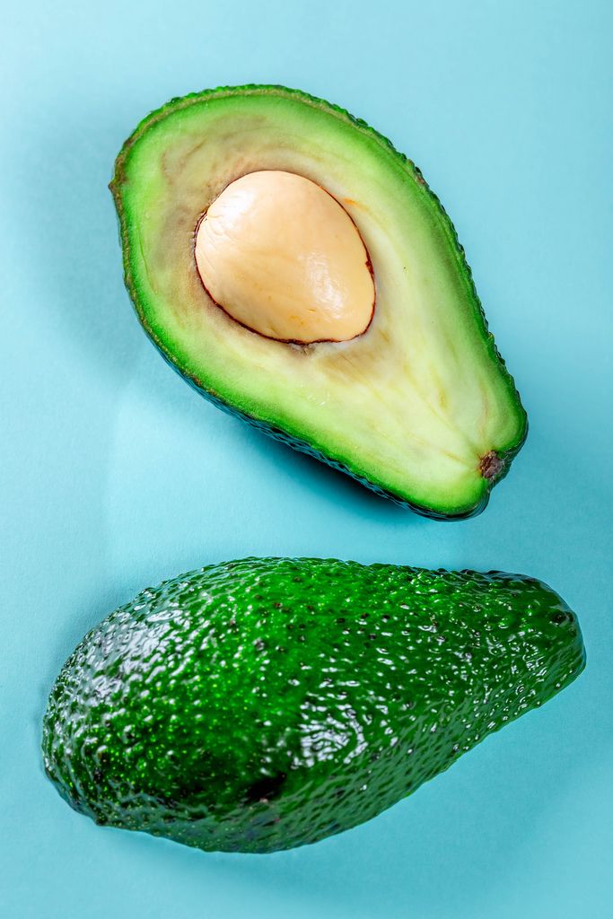 Two halves of green avocado on a blue background