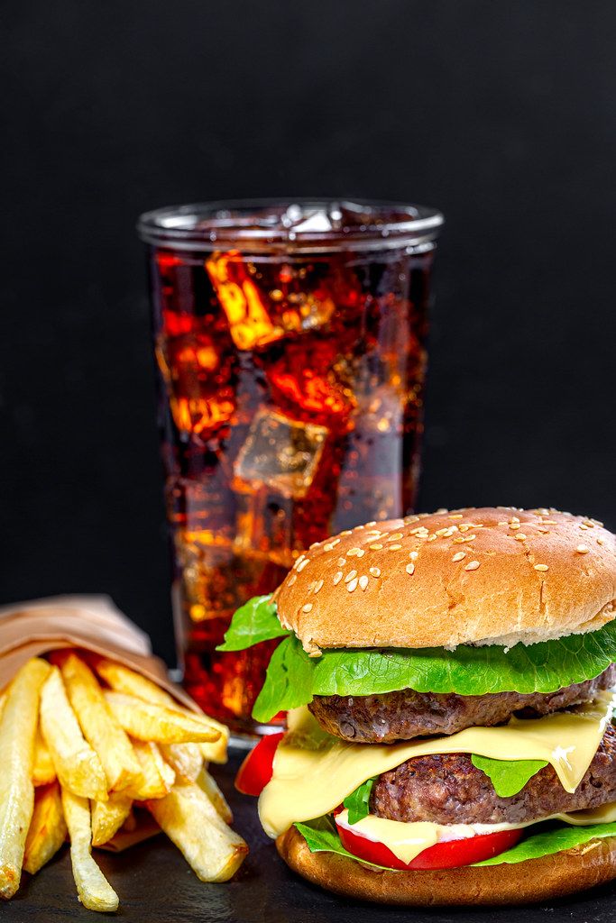 Unhealthy food concept-hamburger, Cola with ice cubes and fried artofel on black background (Flip 2019)