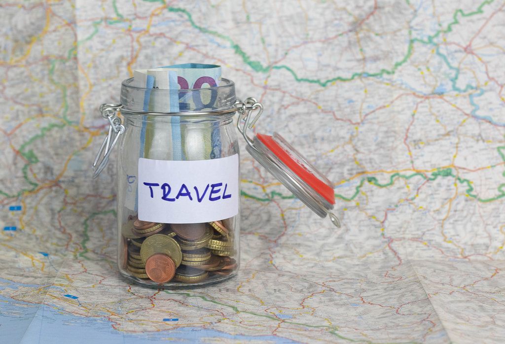 Vacation money savings in a glass jar on world map