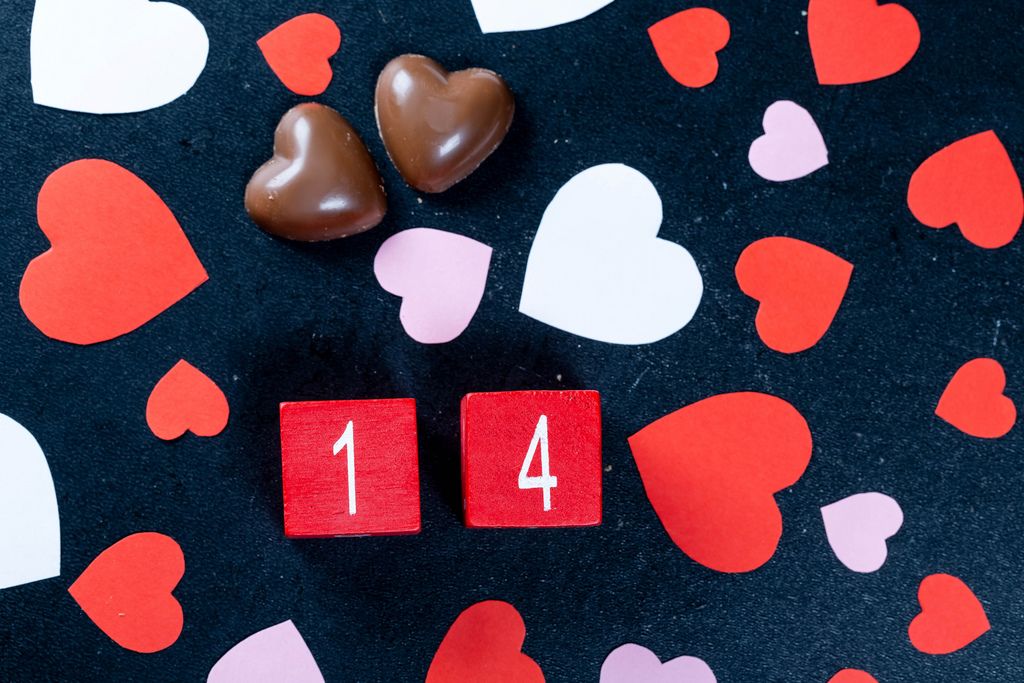 Valentine's date with chocolate and paper hearts on black background