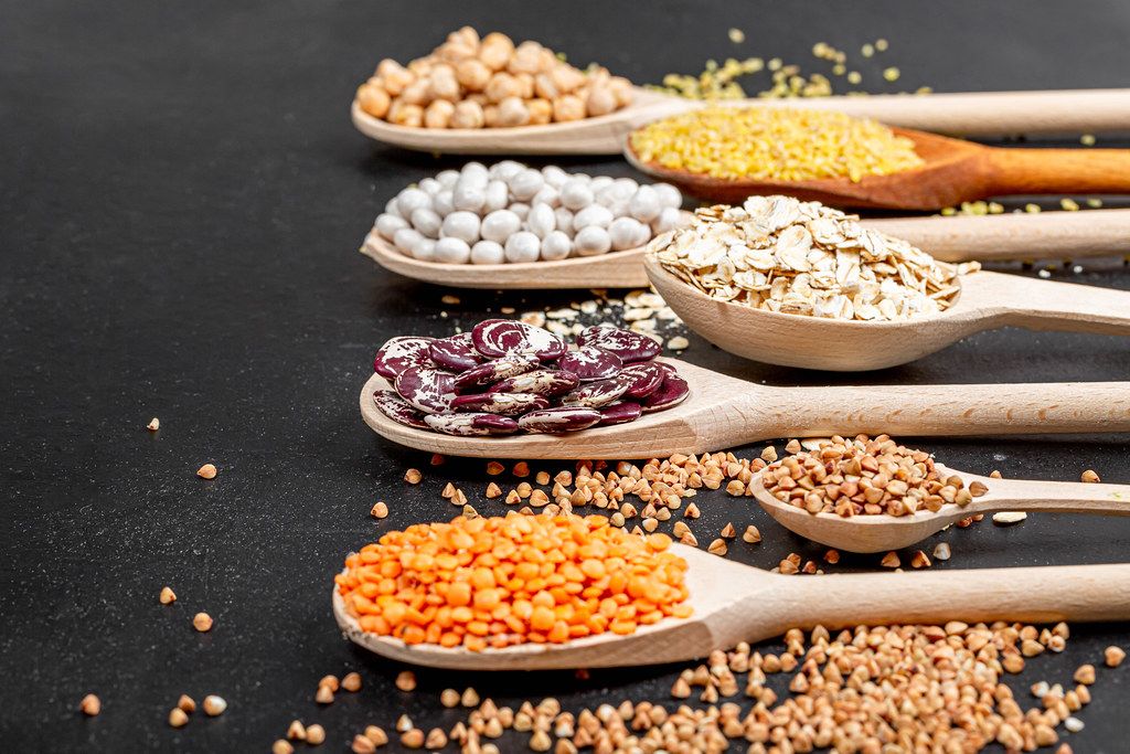 Various cereals and legumes in wooden spoons
