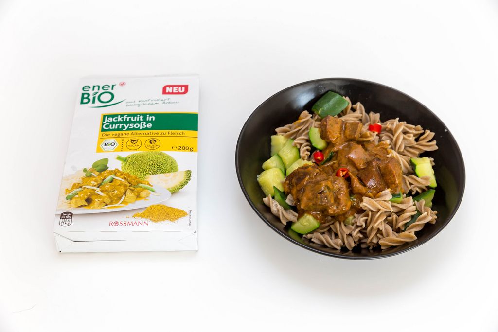 Vegan pasta with jackfruit, cucumber and paprika in currysauce - Rossmann packaging next to the meal