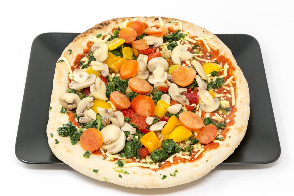 Veganz Pizza Verdura - deep frozen pizza with mushrooms, spinach, paprika and tomatoes on a black plate