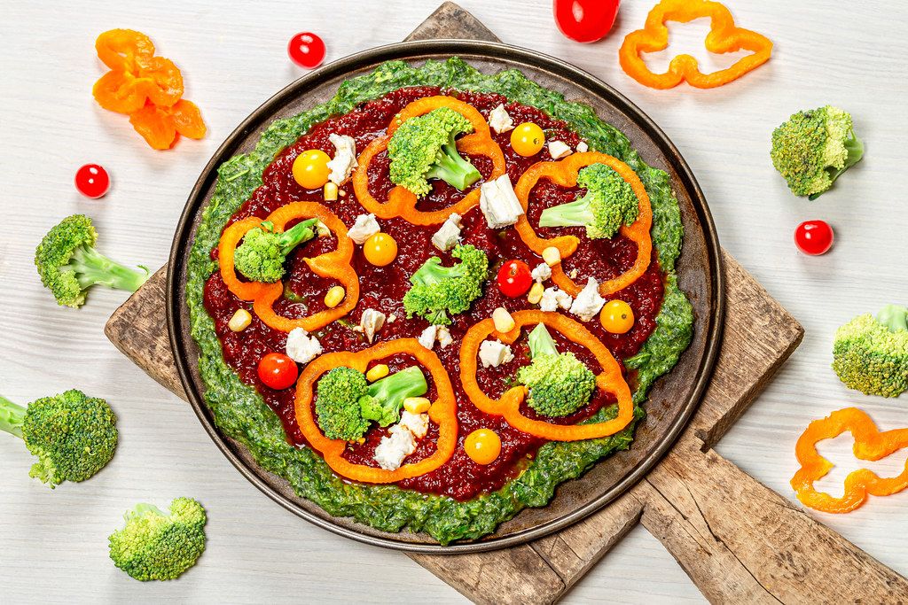 Vegetable pizza with tomatoes, pepper, broccoli and feta cheese with ingredients on the table (Flip 2019)