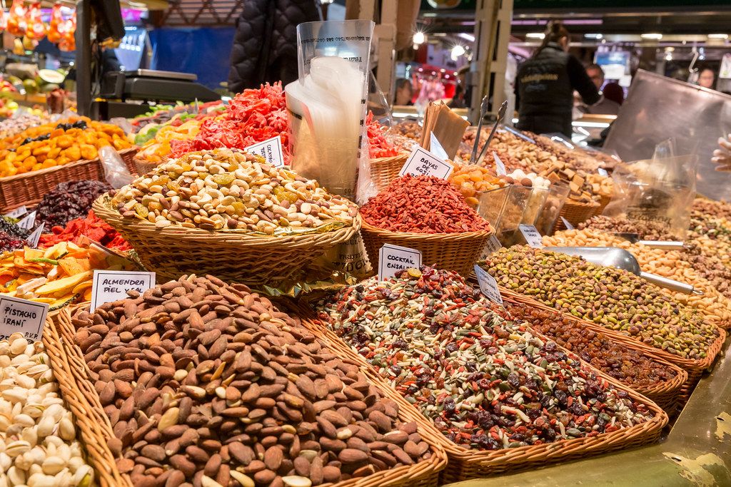 Verschiedene Nüsse und Nussmischungen mit Rosinen, Mandeln und Gojibeeren, in Bastkörben in der größten Markthalle Barcelonas, Spanien