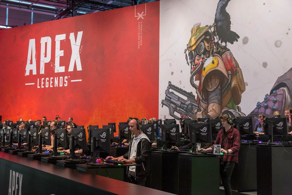 Video game fair visitors  at game stations, playing the Battle Royal game Apex Legends