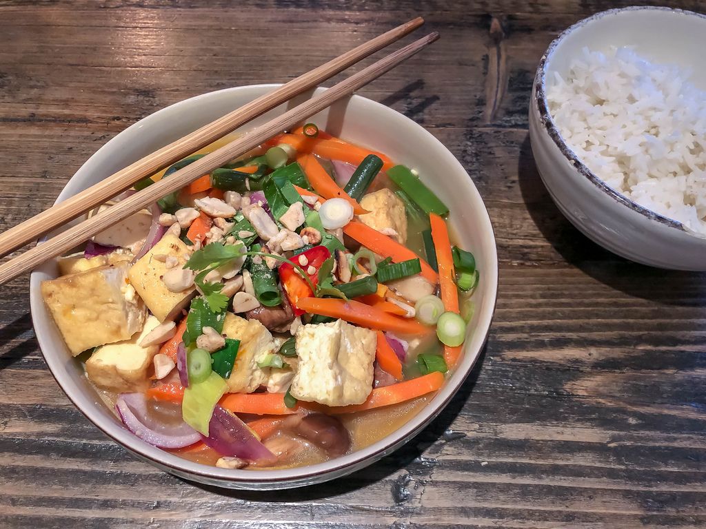 Vietnamese vegetable meal with onions, carrot and pepper in white bowl with chopsticks
