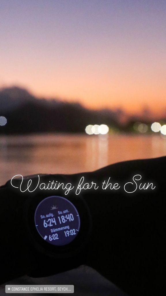 Waiting for the sunrise with Smart Watch showing sunrise hour and the Indian Ocean in the background in Mahé, Seychelles