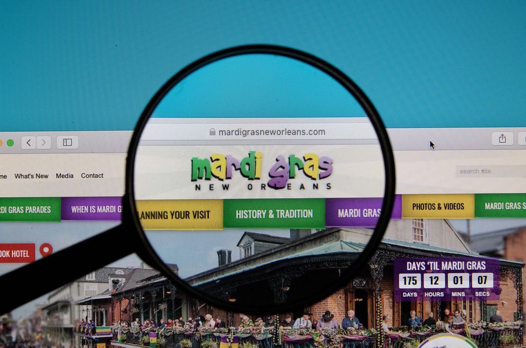 Webseite des Mardi Gras in New Orleans, Louisiana mit durch Lupe hervorgehobenem Logo