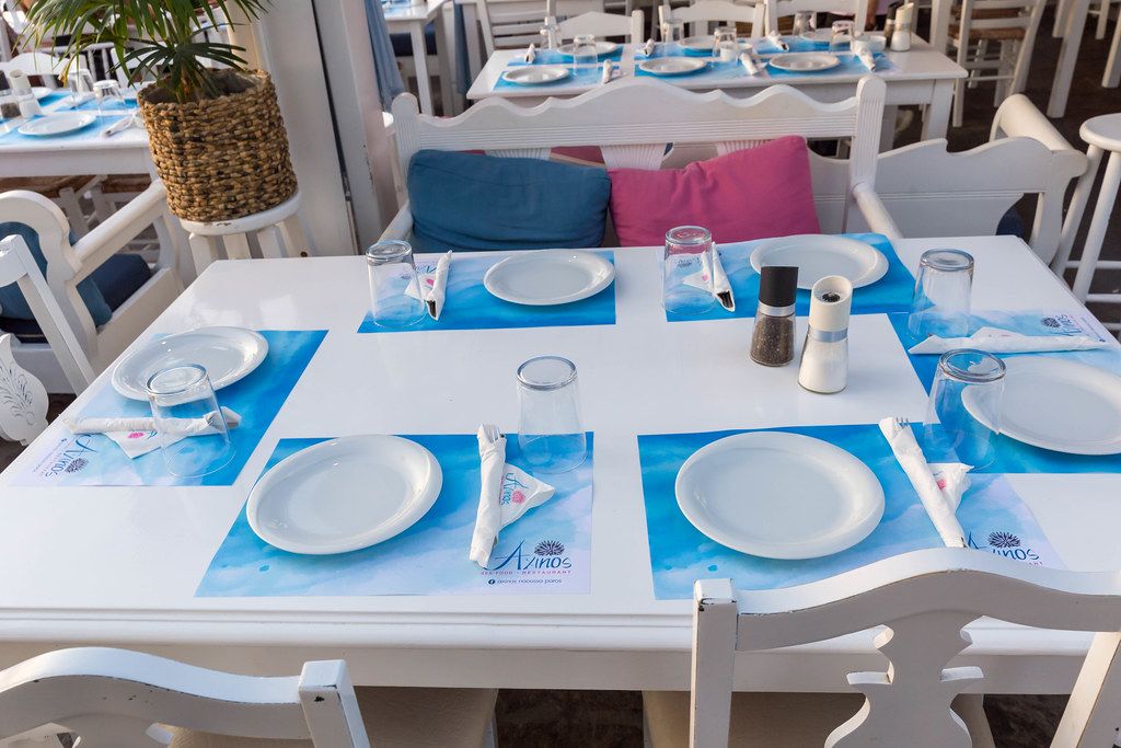 Weißer Tisch in Restaurant auf Paros ist gedeckt in den typisch griechischen Farben blau und weiß
