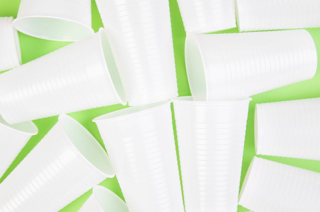 White plastic cups on green background