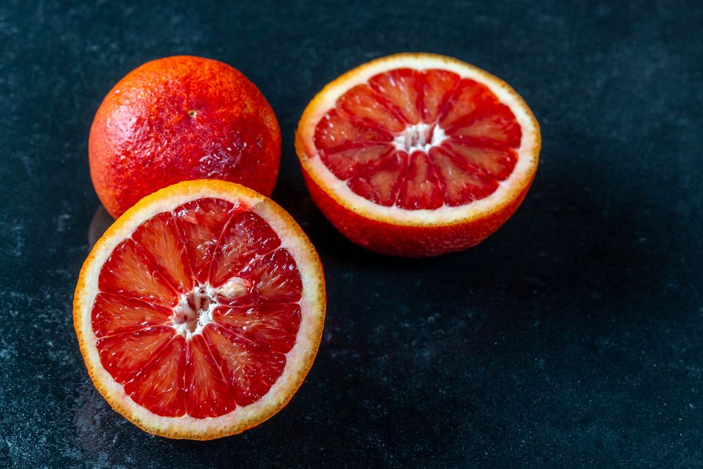 Whole and two halves of red orange on dark background