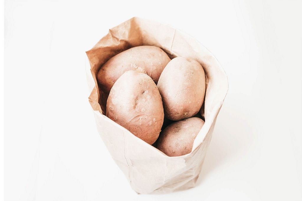 Whole raw potatoes in paper bag on white background (Flip 2019) (Flip 2019) Flip 2019