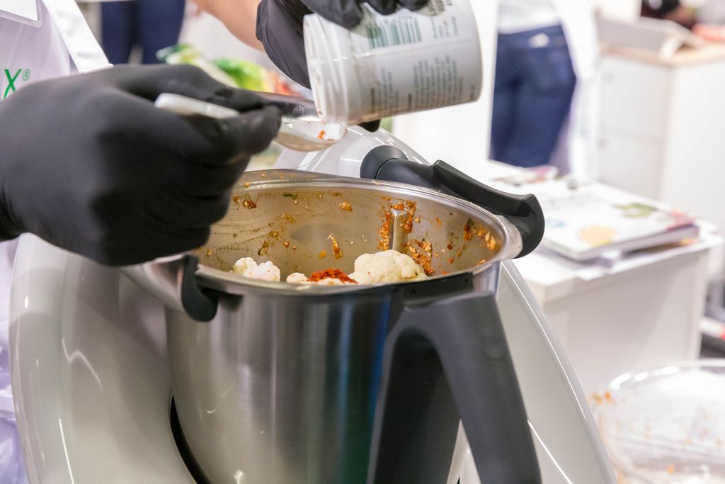 Woman cooks vegetables in the new Thermomix TM6 multifunctional cooker in an open kitchen at Fibo Cologne