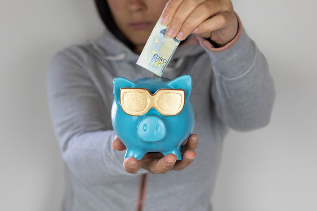 Woman hand putting money bank note into piggy for saving money