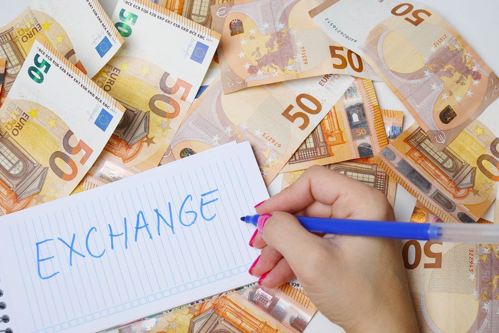 Woman hand writing Exchange, 50 Euro banknotes background