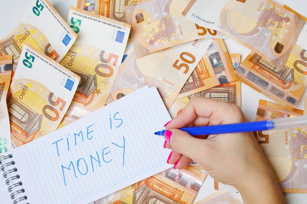 Woman hand writing Time is money, 50 Euro banknotes background