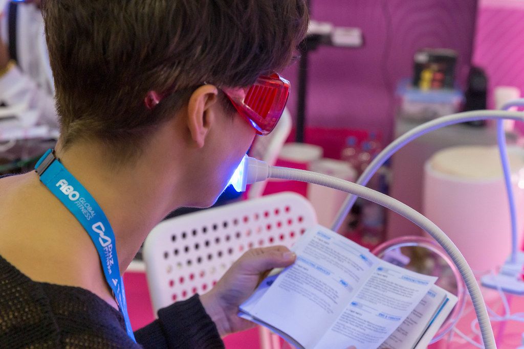 Woman tests teeth whitening system by Only Smile while she comfortably reads at Fibo in Cologne