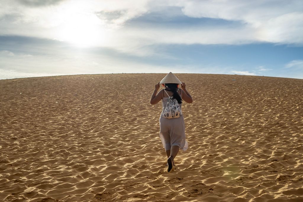 Woman with Vietnamese Hat in the Red Sand Dunes in Mui Ne, Vietnam