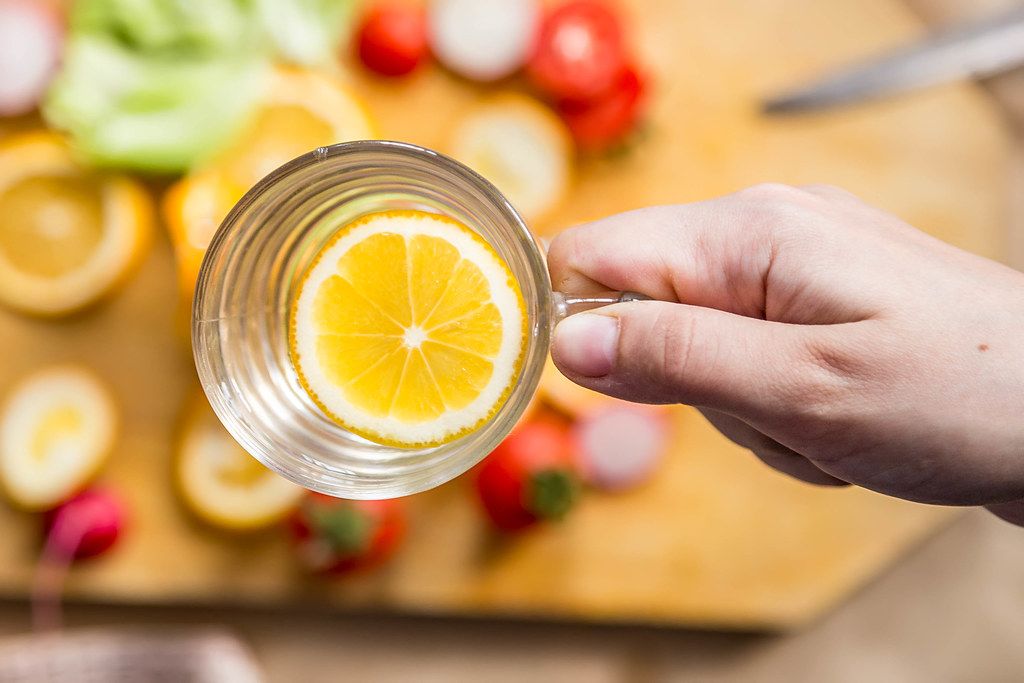 Woman's hand holding a glass of fresh lemon water