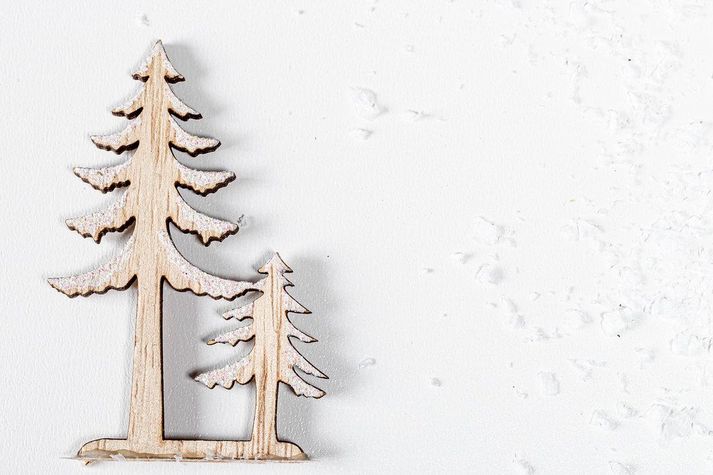 Wooden figures of a large and small Christmas tree on a white background with snow. Top view (Flip 2019)