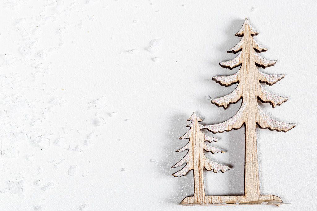 Wooden figures of a large and small Christmas tree on a white background with snow. Top view