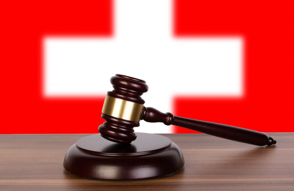 Wooden gavel and flag of Switzerland