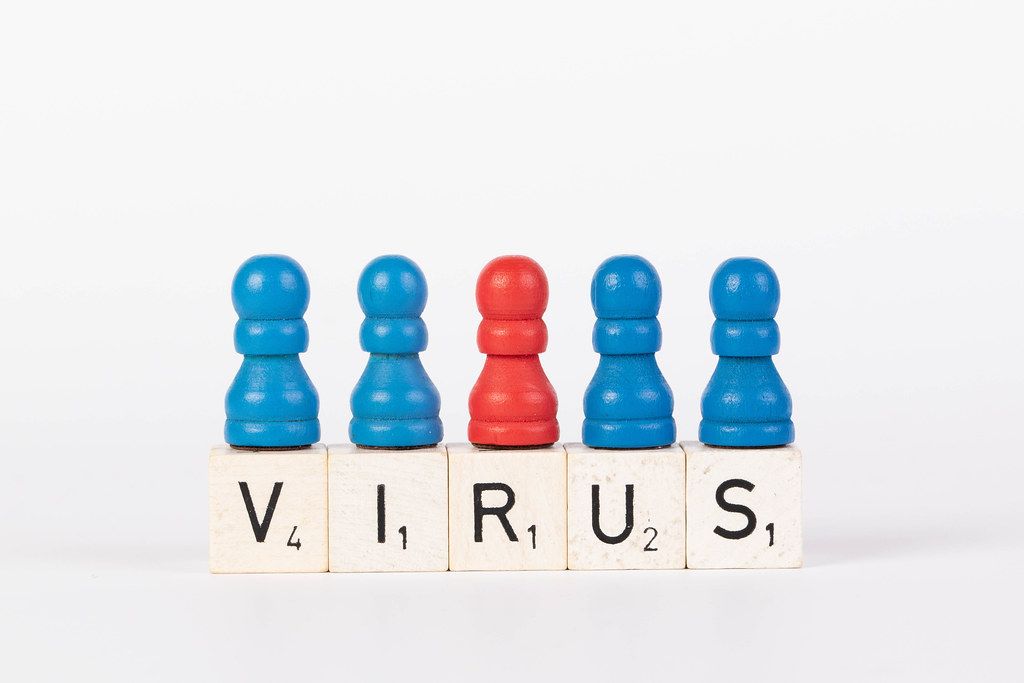 Word Virus written on wooden blocks with pawns in various colors on white background