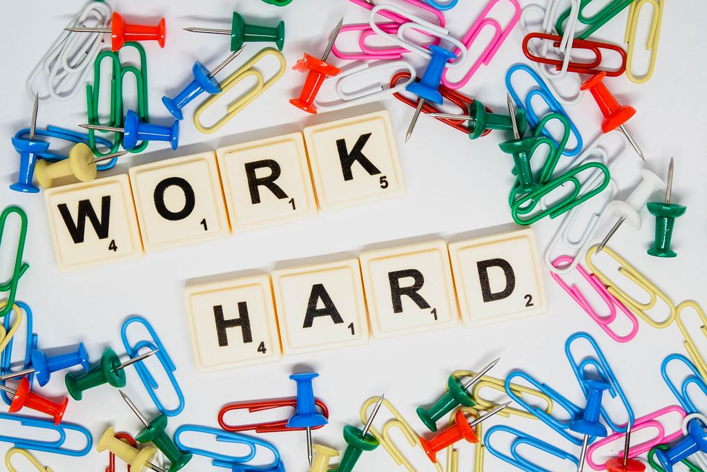 Work hard text with colorful pins and clips on white surface