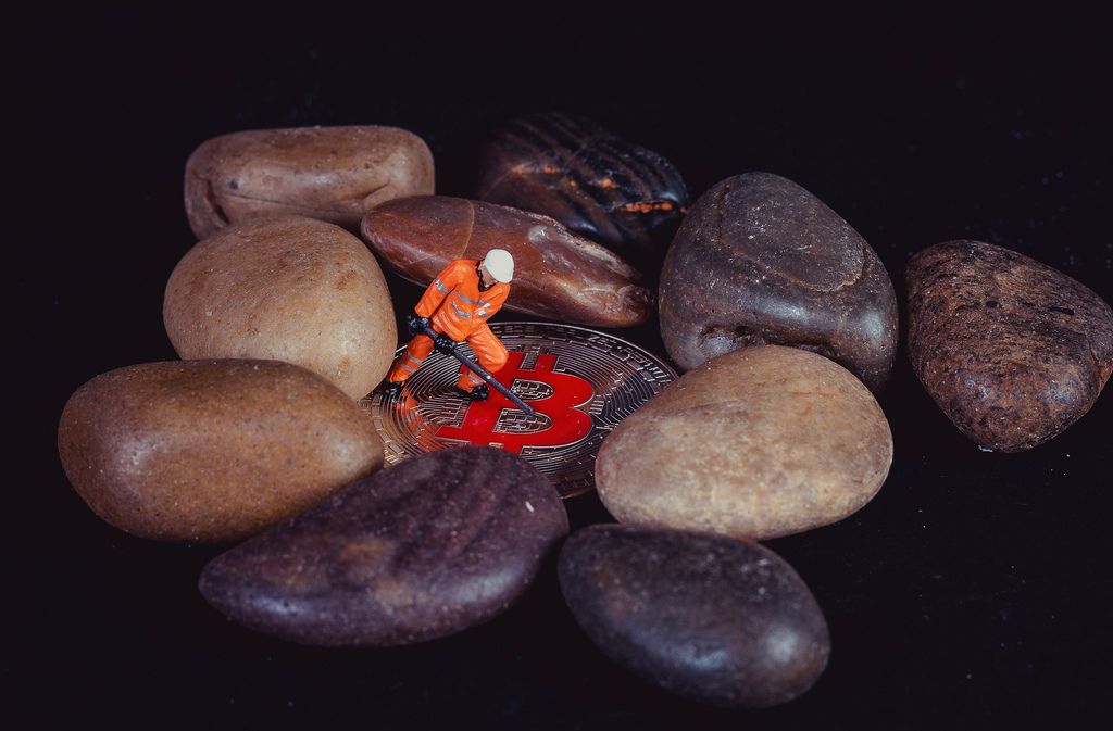 Worker standing on Bitcoin between rocks