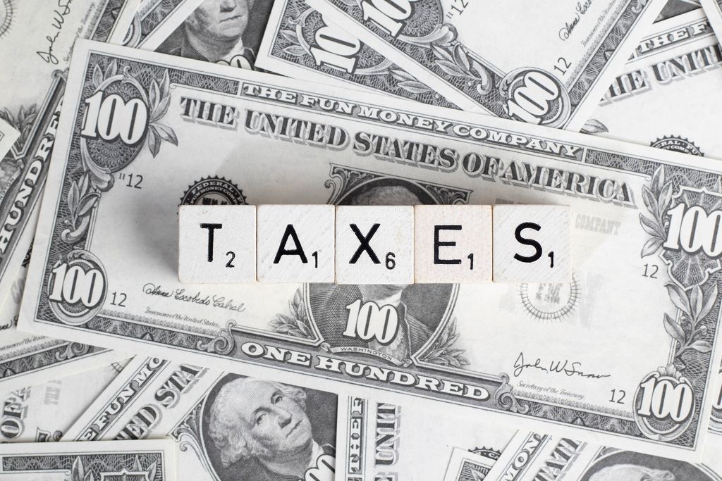 Wort TAXES (Steuern) mit Würfel gebildet auf verteilten US-Dollar Banknoten