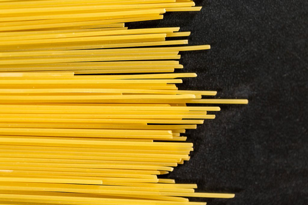 Yellow long spaghetti on black background.
