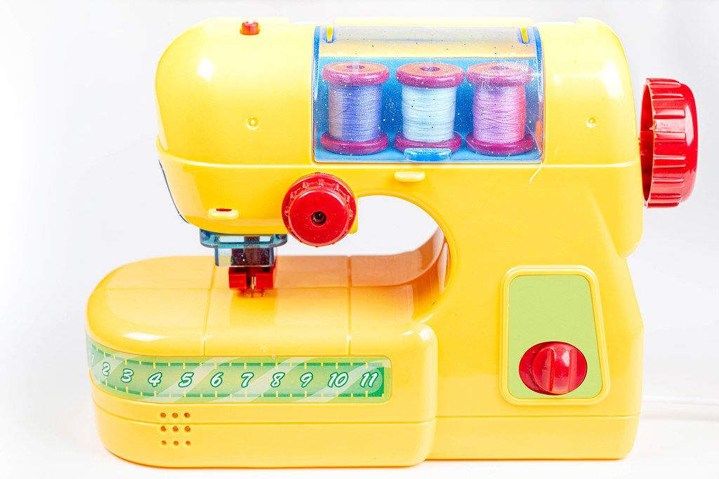 Yellow plastic sewing machine-toy for children on a white background