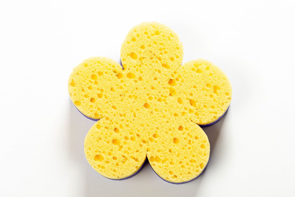 Yellow washcloth in the shape of a flower on white background (Flip 2019)