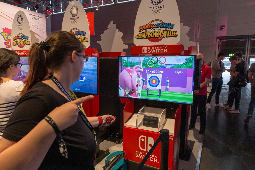 Young woman tests virtual archery sports of the video game Mario&Sonic at The Olympic Games, at the Nintendo Switch game station at Gamescom