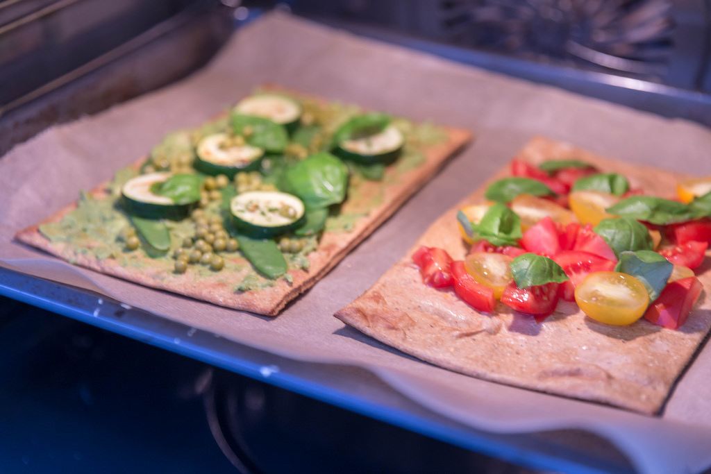 Zwei vegane Pizzen mit frischen Zutaten belegt im Ofen - Creative ...