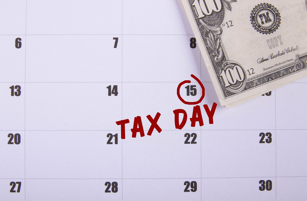100 dollar banknote and Tax Day text on the calendar
