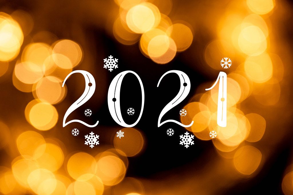 2021 with white snowflakes on golden bokeh