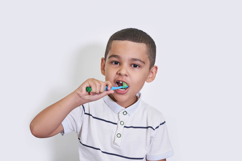 7-8 years old kid boy in white shirt brush his teeth with toothbrush
