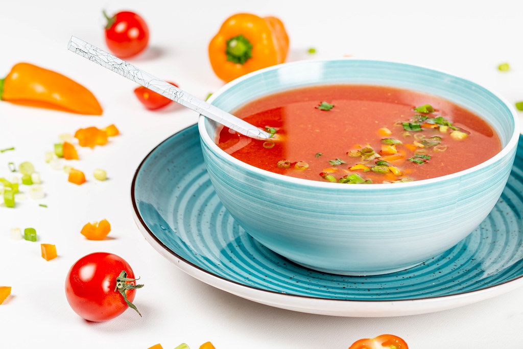 A bowl of fresh tomato soup with herbs and bell pepper