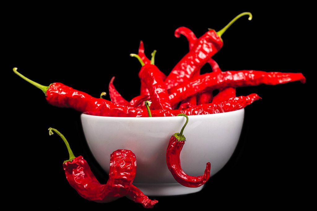 A bowl of hot red pepper on a dark background