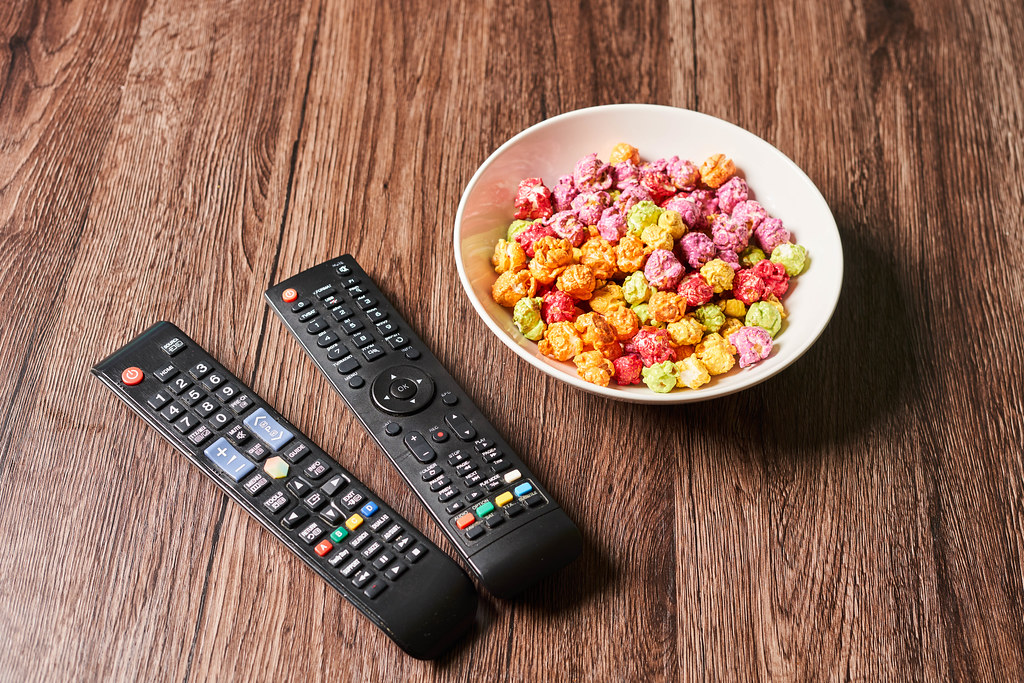 A bowl with sweet popcorns and remote controls for TV