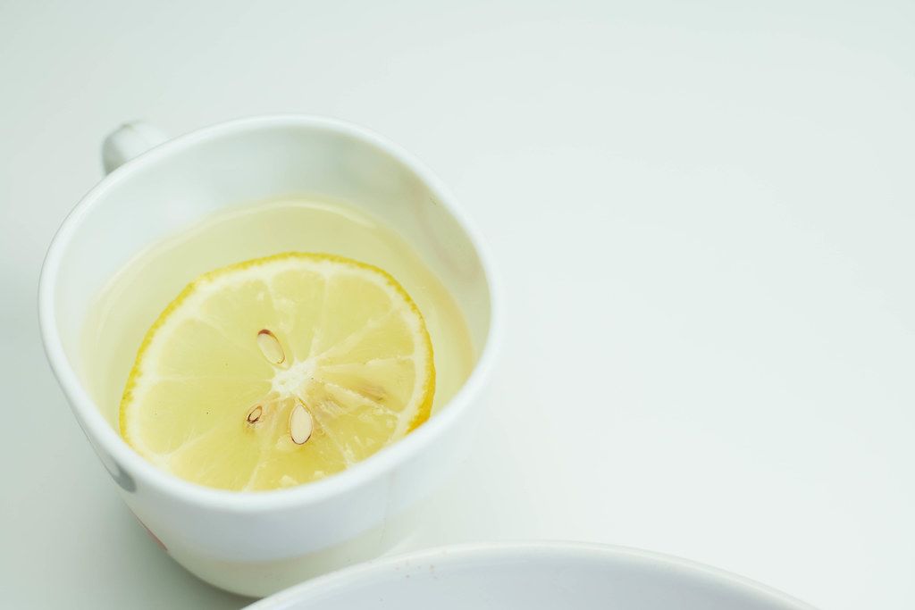 A cup of water with fresh citrus fruit lemon