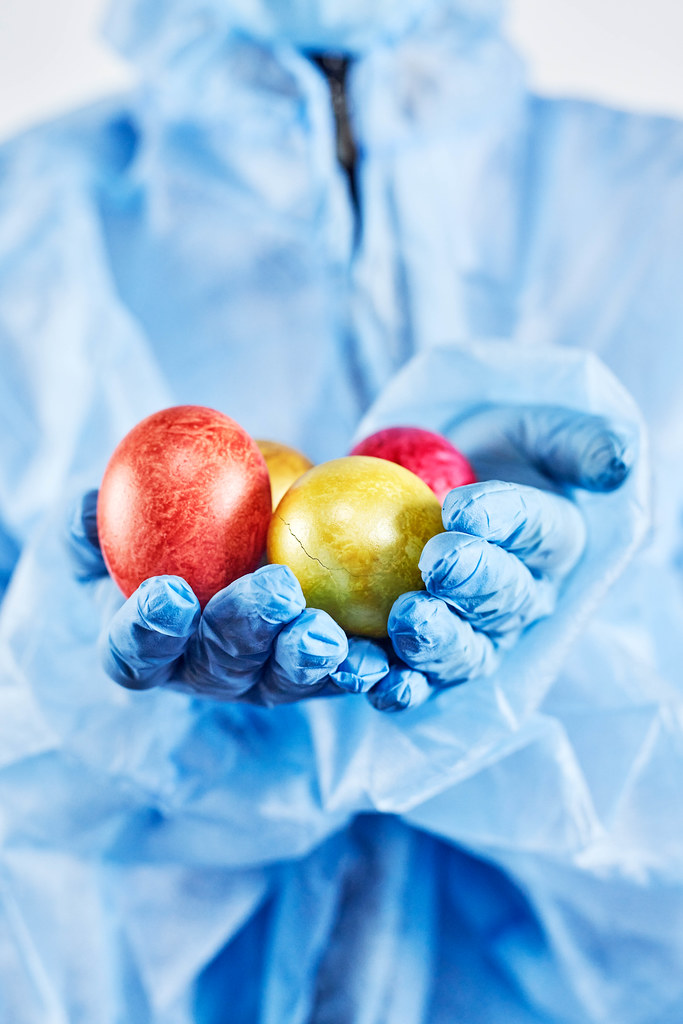 A doctor in medical protective clothing holds colorful Easter eggs